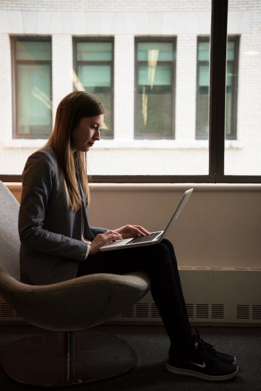 Woman Sits and Use Laptop Computer Near Window